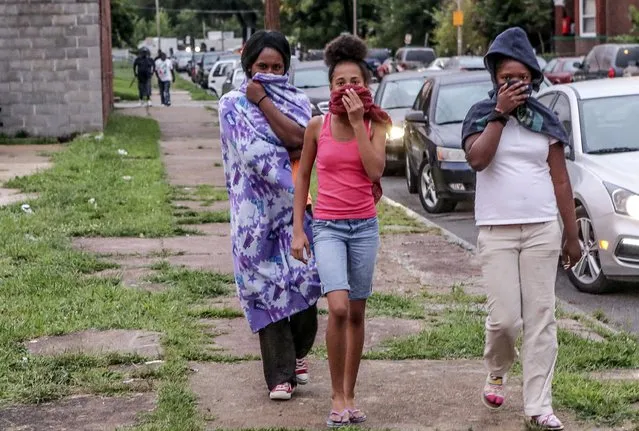 Neighborhood residents cover their faces as the St. Louis Police Department used tear gas to disperse the growing crowd due to a police shooting earlier in the day in St. Louis, Missouri August 19, 2015. (Photo by Lawrence Bryant/Reuters)