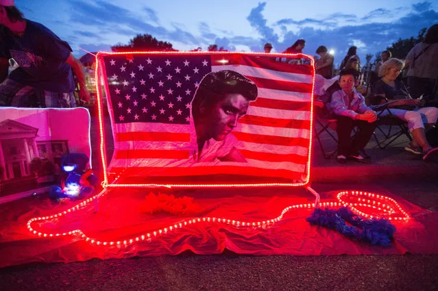 A street memorial is lit during a candlelight vigil for Elvis Presley in front of Graceland, Presley's Memphis home, on Tuesday, August 15, 2017, in Memphis, Tenn. Fans from around the world are at Graceland for the 40th anniversary of his death. Presley died Aug. 16, 1977. (Photo by Brandon Dill/AP Photo)