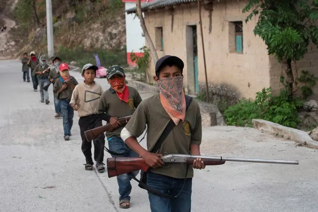 Children walk in a single file, holding toy and real guns, as they demonstrate newly learnt skills from military-style weapons training, to a Reuters journalist, in Ayahualtempa, Mexico, February 3, 2020. (Photo by Alexandre Meneghini/Reuters)