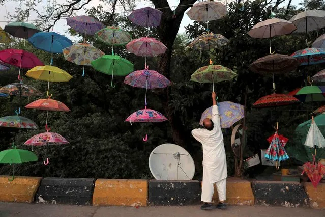 A customer buys an umbrella on a roadside in Murree, near Islamabad, Pakistan, Friday, May 6, 2022. (Photo by Rahmat Gul/AP Photo)