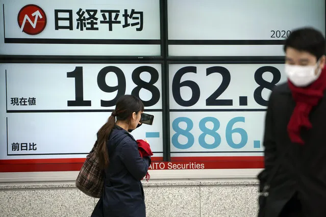 A woman takes a photo of an electronic stock board showing Japan's Nikkei 225 index at a securities firm in Tokyo Monday, March 9, 2020. Asian stock markets plunged Monday after global oil prices nosedived on worries a global economy weakened by a virus outbreak might be awash in too much crude. Tokyo's benchmark tumbled 4.7%. (Photo by Eugene Hoshiko/AP Photo)