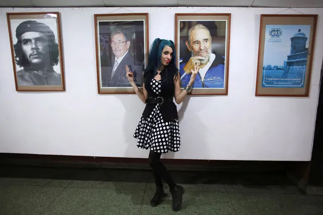 Bexy Estopina, 21, poses for a photographer (not pictured) in front of pictures of Cuba's former President Fidel Castro (R), Cuba's President Raul Castro (C) and late Cuban revolutionary hero Ernesto “Che” Guevara during the Cuban Otaku festival at a cinema in Havana, Cuba, July 24, 2016. (Photo by Alexandre Meneghini/Reuters)