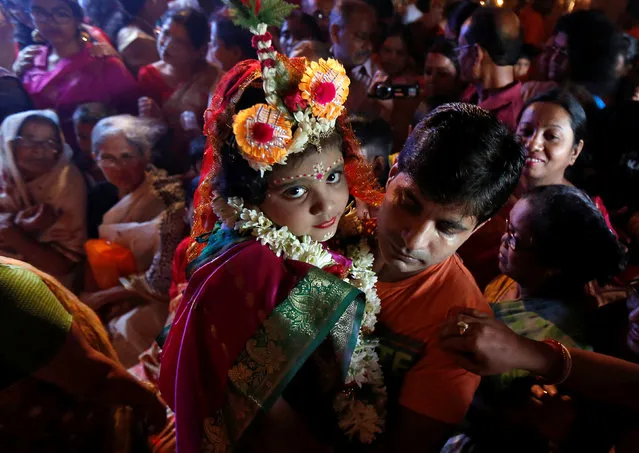 Soumili Mukherjee, a five-year old girl dressed as a Kumari, who is worshipped as part of the Durga Puja rituals, is carried by her father to a temporary platform called pandal, during the Hindu religious festival Durga Puja in Kolkata, September 28, 2017. (Photo by Rupak De Chowdhuri/Reuters)