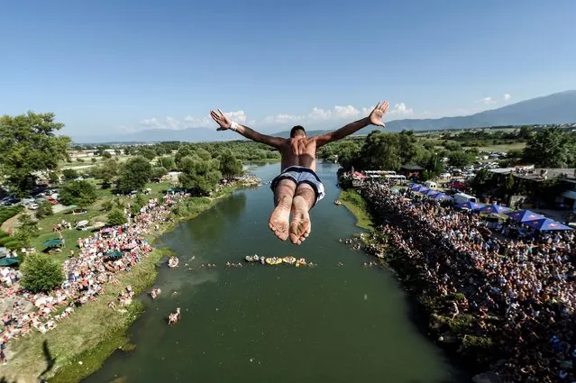People look at a man as he jumps from the 22 meters high bridge Ura during the High Diving competition near the town of Gjakova on July 31, 2016. (Photo by Armend Nimani/AFP Photo)