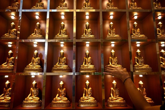 A man arranges Buddha statues in preparation for the upcoming Lunar New Year of the Snake at Vihara Buddhayana in Surabaya on January 20, 2025. (Photo by Juni Kriswanto/AFP Photo)