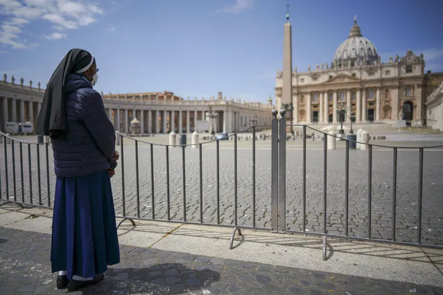 A nun waits for Pope Francis to deliver his blessing from the window of his studio overlooking an empty St. Peter's Square, due to anti-coronavirus lockdown measures, at the Vatican, Sunday, May 10, 2020. Pope Francis is calling on leaders of European Union nations to work together on the social and economic consequences of the COVID-19 pandemic. (Photo by Andrew Medichini/AP Photo)