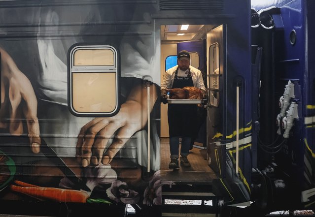 A chef serves turkey to railway workers to celebrate Thanksgiving Day from a train-kitchen named Food Train designed to make and distribute up to 70,000 meals a week as the train prepares to set off on its maiden journey from Ukrainian capital to frontline areas in the eastern region, amid Russia's attack on Ukraine, in Kyiv, Ukraine on November 23, 2023. (Photo by Gleb Garanich/Reuters)