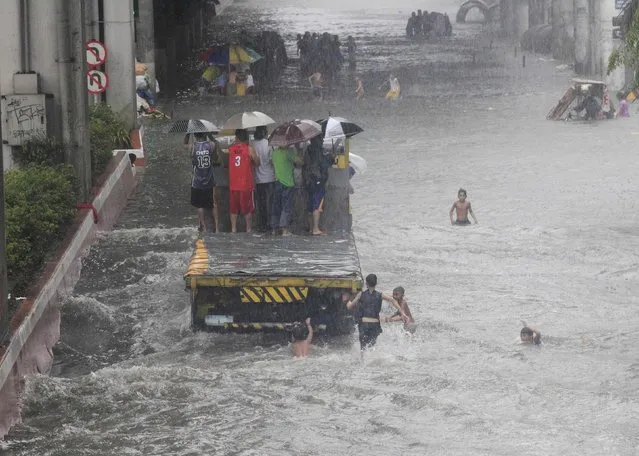 Stranded passengers ride on a truck to cross a flooded street after tropical storm Fung-Wong battered metro Manila September 19, 2014. (Photo by Erik De Castro/Reuters)