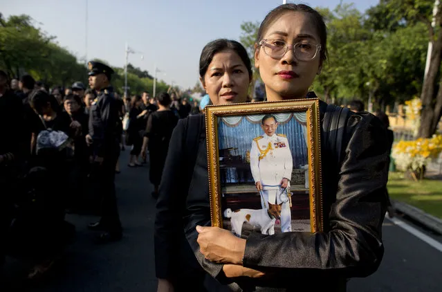 Thai mourners, carrying a portrait of late Thai King Bhumibol Adulyadej gather in front of a replica of the royal crematorium in Bangkok, Thailand, Thursday, October 26, 2017. Bhumibol's death at age 88 after a reign of seven decades sparked a national outpouring of grief and a year of mourning, culminating in an elaborate funeral and cremation ceremony this week. (Photo by Gemunu Amarasinghe/AP Photo)