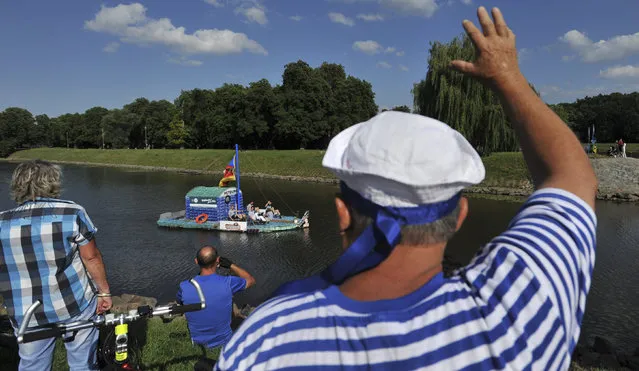 People wave as Jakub Bures, Jan Kara, Jan Brand and Jan Holan pedal their boat, made with plastic bottles, during an official launch on the Elbe river in Nymburk July 12, 2014. (Photo by Rene Volfik/Reuters)