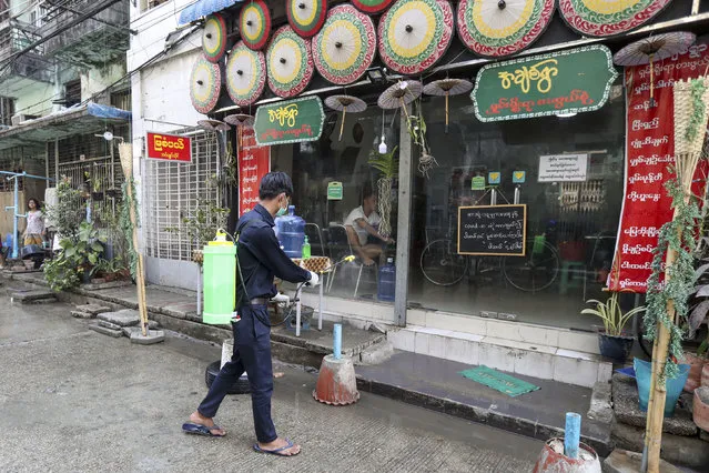 A member of Yangon City and Development Committee sprays disinfectant near a restaurant on a street in hopes of curbing the spread of the new coronavirus in Yangon, Myanmar Wednesday, March 25, 2020. (Photo by Thein Zaw/AP Photo)