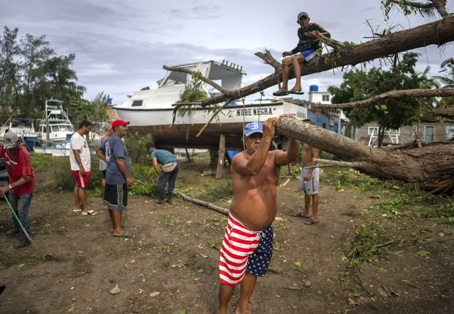 People rest as they cut down a tree that fell on top of a boat due to Hurricane Ian in Havana, Cuba, Wednesday, September 28, 2022. (Photo by Ramon Espinosa/AP Photo)