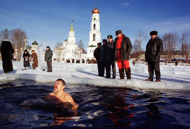 A Russian man bathes in ice-cold water as others pray to mark the Russian Orthodox Epiphany January 19, 2001 near Raifa man''s monastery in Raifa, Tatarstan, Russia as the Russian Orthodox Church marks the Epiphany. Photo by Oleg Nikishin/Newsmakers)