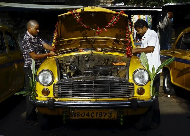 Drivers decorate a yellow ambassador taxi to celebrate the festival of Vishwakarma Puja or the festival of the Hindu deity of architecture and machinery, outside a temple in Kolkata, India, September 18, 2015. (Photo by Rupak De Chowdhuri/Reuters)