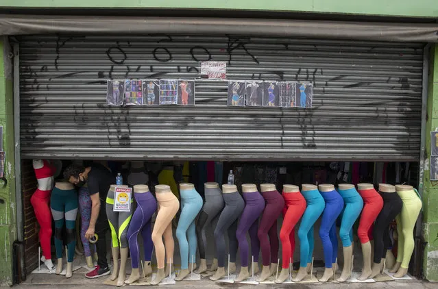 A store worker opens a clothing shop in a downtown shopping district of Sao Paulo, Brazil, Wednesday, June 10, 2020. Retail shops reopened on Wednesday in Brazil's biggest city after a two-month coronavirus pandemic shutdown that aimed to contain the spread of the new coronavirus. (Photo by Andre Penner/AP Photo)
