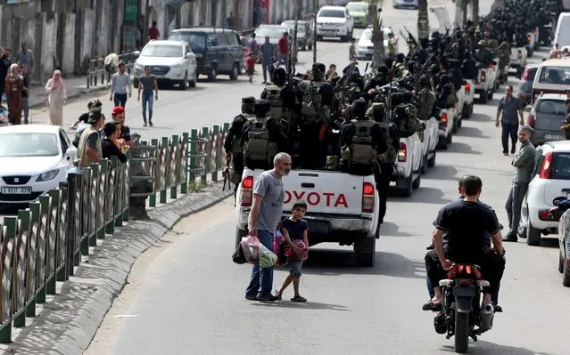 A man walks with his son as Palestinian Islamic Jihad militants ride on pick up trucks during a symbolic funeral for Ramadan Shallah, a former leader of their group, in Gaza City on June 7, 2020. (Photo by Mohammed Salem/Reuters)