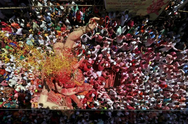 An idol of Hindu god Ganesh, the deity of prosperity, is showered with coloured powder and flowers as it is taken through a street on the last day of the ten-day-long Ganesh Chaturthi festival in Mumbai, India, September 27, 2015. (Photo by Danish Siddiqui/Reuters)