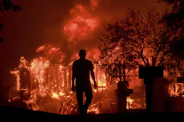 Jim Stites watches part of his neighborhood burn in Fountaingrove, Calif., on October 9, 2017, as more than a dozen wildfires whipped by powerful winds burn though California wine country. (Photo by Kent Porter/The Press Democrat via AP Photo)