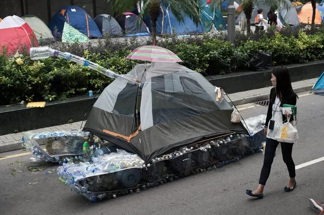 A woman walks past a tank made out of an umbrella, a tent and used plastic bottles in the Admiralty district of Hong Kong on October 24, 2014. A United Nations rights watchdog pressed Hong Kong to enact democratic reforms, saying moves so far fell short of what was needed. (Photo by Nicolas Asfouri/AFP Photo)