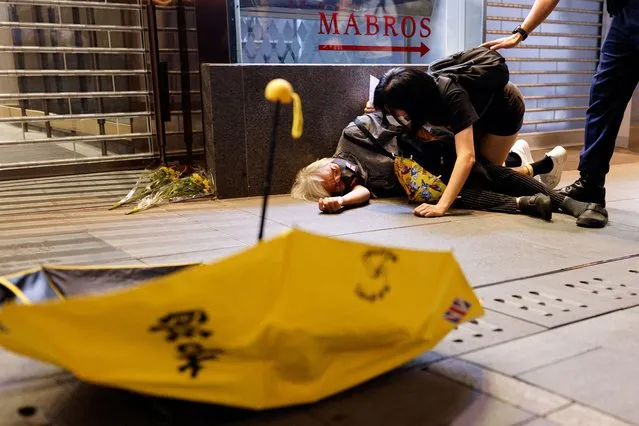 A protester lies on the ground after being pushed during a protest over coronavirus disease (COVID-19) restrictions in mainland China, during a commemoration of the victims of a fire in Urumqi, in Hong Kong, China on November 28, 2022. (Photo by Tyrone Siu/Reuters)