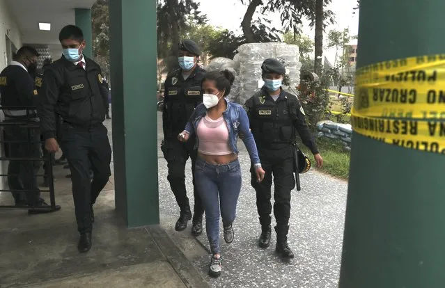 Police officers escort a woman who was detained at a disco where thirteen people died during a stampede in Lima, Peru, Sunday, August 23, 2020. (Photo by Martin Mejia/AP Photo)