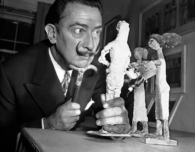 Resting his chin on the handle of his cane, Spanish surrealist painter Salvador Dali studies an exhibit of contemporary Greek art in New York, January 4, 1956.  Dali called his trademark mustache his “inspirational antenna”. (Photo by Robert Kradin/AP Photo)