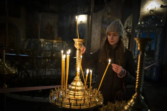 A girl lights a candle before the start of the Orthodox Christmas in the St. Michael's Monastery of Kyiv, Ukraine, Friday, January 6, 2023. Russian President Vladimir Putin on Thursday ordered Moscow's armed forces to observe a 36-hour cease-fire in Ukraine this weekend for the Russian Orthodox Christmas holiday, but Ukrainian President Volodymyr Zelenskyy questioned the Kremlin's intentions. (Photo by Bela Szandelszky/AP Photo)