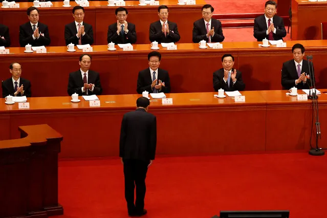 Chinese President Xi Jinping and other top officials clap their hands as Chinese Premier Li Keqiang bows before delivering his speech during the opening session of the National People's Congress (NPC) at the Great Hall of the People in Beijing, China on March 5, 2018. (Photo by Damir Sagolj/Reuters)