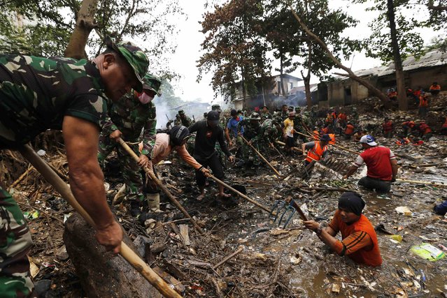 Soldiers and volunteers clear rubbish from the Ciliwung River in the Jatinegara district of Jakarta, December 3, 2014. (Photo by Reuters/Beawiharta)