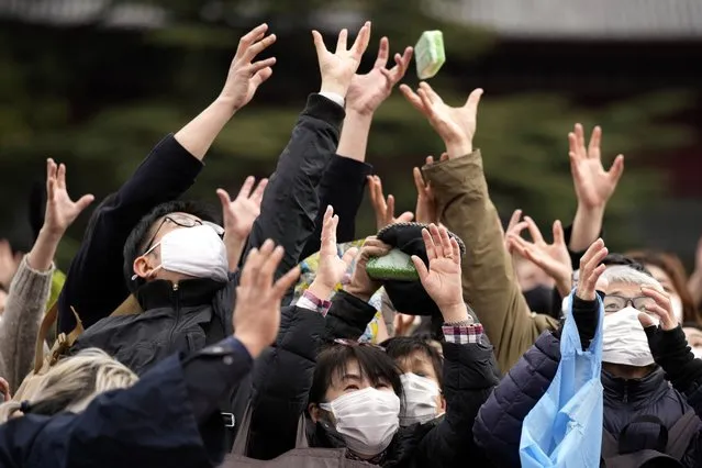 People try to catch lucky beans scattered by celebrities during the “Mame-maki”, a bean throwing ceremony, at the Zojoji Buddhist temple Friday, February 3, 2023, in Tokyo. The ritual believed to bring in good luck and drive away evil is performed annually to mark the beginning of the spring in the lunar calendar. (Photo by Eugene Hoshiko/AP Photo)