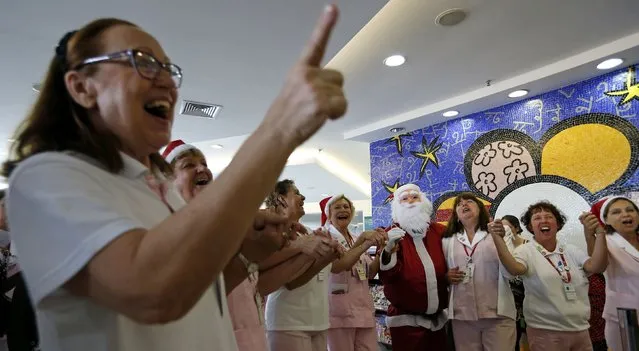 A man dressed as Santa Claus dances with nurses at the Cancer Institute in Sao Paulo December 19, 2014. (Photo by Paulo Whitaker/Reuters)