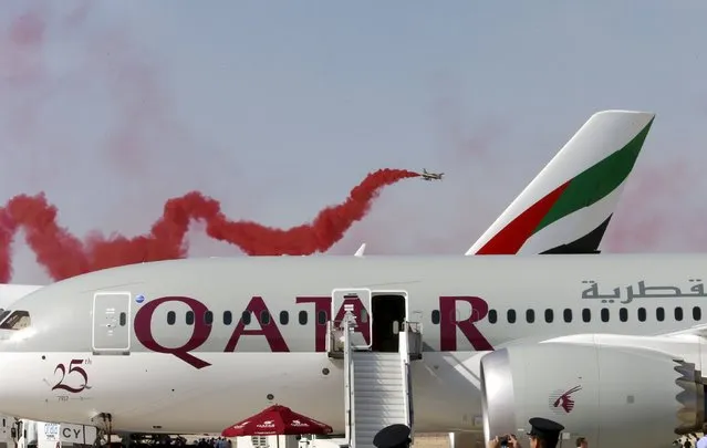 A performance by Al Fursan, the aerobatics demonstration team of the UAE Air Force, is seen behind a Qatar Airways plane at the Dubai Airshow November 8, 2015. (Photo by Ahmed Jadallah/Reuters)