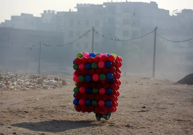 A man carries children's coloured plastic balls on his motorcycle in Delhi, India, March 20, 2018. (Photo by Cathal McNaughton/Reuters)