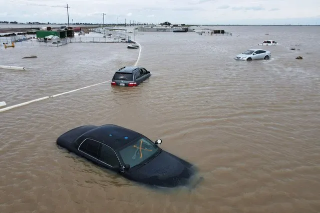 Car sit abandoned on roads as floodwaters from the Tule River inundate the area after days of heavy rain in Corcoran, California, U.S., March 21, 2023. (Photo by David Swanson/Reuters)