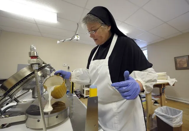 Sister Rebecca Leis pours low-gluten alter bread batter into a machine that bakes the thin bread at the Benedictine Sisters of Perpetual Adoration monastery in Clyde, Missouri, December 18, 2014. The Sisters have made communion wafers since 1910 and began making a low-gluten version in 2003 and have gone from 143 customers in 2004 to more than 11,000 customers from around the world. (Photo by Dave Kaup/Reuters)