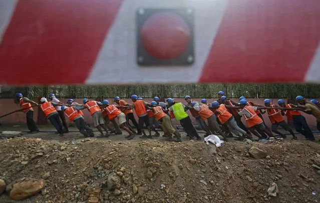 Workers pull as they work to remove a high voltage underground electrical cable on side of a road in Mumbai May 17, 2013. (Photo by Danish Siddiqui/Reuters)