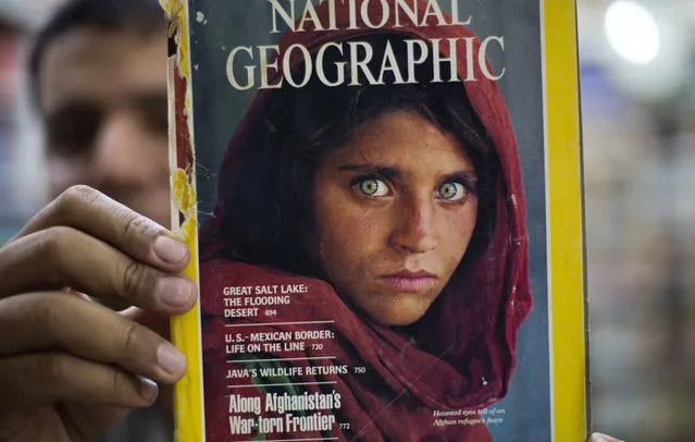 Pakistan's Inam Khan, owner of a book shop shows a copy of a magazine  with the photograph of Afghan refugee woman Sharbat Gulla, from his rare collection in Islamabad, Pakistan, Wednesday, October 26, 2016. A Pakistani investigator says the police have arrested National Geographic's famed green-eyed “Afghan Girl” for having a fake Pakistani identity card. Shahid Ilyas from the Federal Investigation Agency, says the police arrested Sharbat Gulla during a raid on Wednesday at a home in Peshawar. (Photo by B.K. Bangash/AP Photo)
