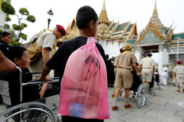 A mourner holds a bag with a picture of Thailand's late King Bhumibol Adulyadej while lining up to enter the Throne Hall for the first time to pay his respects in front of the golden urn of the late king in Bangkok, Thailand, October 29, 2016. (Photo by Jorge Silva/Reuters)