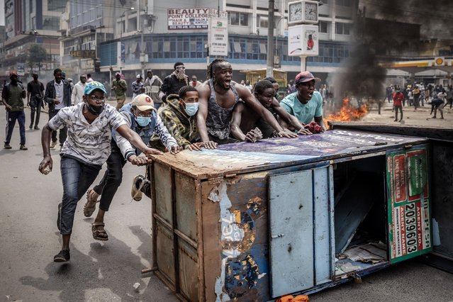 Protesters chant slogans as they use urban furniture as a barricade to clash with Kenya Police officers during an anti-government demonstration called following nationwide deadly protests over tax hikes and a controversial now-withdrawn tax bill in downtown Nairobi, on July 2, 2024. Kenyan police fired tear gas to scatter small crowds in the capital Nairobi on Tuesday, AFP reporters saw, after youth activists called for fresh protests following deadly violence during anti-tax hike demonstrations last month. (Photo by Luis Tato/AFP Photo)