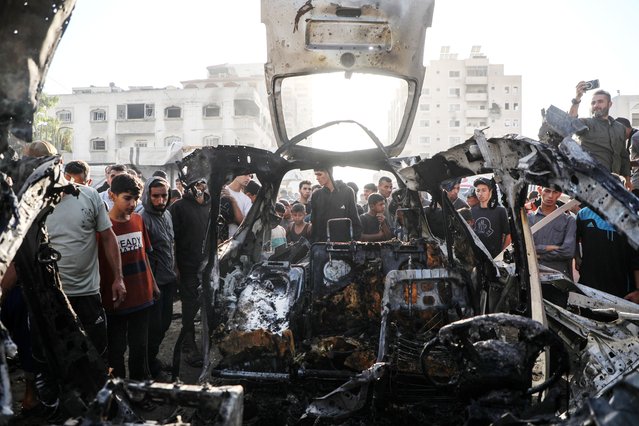 Palestinians gather around a destroyed vehicle in west of Gaza City, on November 22, 2025. Gaza's Civil Defense said on Saturday that Israel launched a series of airstrikes on the Gaza Strip, resulting in at least 22 deaths and dozens of injuries in the enclave. A Hamas source, speaking on condition of anonymity, told Xinhua that the movement has informed regional mediators of its “anger” over continued Israeli attacks on the Gaza Strip, despite Hamas and other Palestinian factions adhering to the ceasefire agreement. (Photo by Xinhua News Agency/Rex Features/Shutterstock)