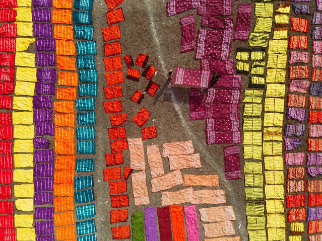 Hundreds of colour-dyed sheets of cloth are spread across a field for drying in Narayanganj, Bangladesh on October 28, 2025. The colorful cloths which sell for less than 3 USD are arranged on patches of grass to dry out completely as it is cheaper and more sustainable to dry them out in sunlight. Once the fabrics are dried, they are made into garments like t-shirts and dresses before being sold across the world. (Photo by Joy Saha/ZUMA Press Wire via Alamy Live News)