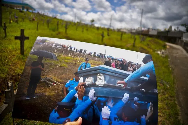 A printed photo taken on September 29, 2017 showing police lifting the coffin of officer Luis Angel Gonzalez Lorenzo, who was killed during the passage of Hurricane Maria when he tried to cross a river in his car, is shown at the same cemetery in Aguada, Puerto Rico, May 31, 2018. The local police force of Aguadilla and Aguada lacks about a dozen officers since the storm, due to resignations and retirements. The U.S. territory's bankruptcy has frozen promotions, salaries, new hires and some police academies have even closed. (Photo by Ramon Espinosa/AP Photo)