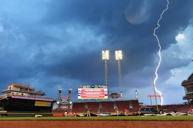 Grounds crew pull the tarp on the field as lightning from an approaching storm strikes in the distance during a game between the Cincinnati Reds and the Milwaukee Brewers at Great American Ball Park on September 5, 2015 in Cincinnati. (Photo by Jamie Sabau/Getty Images)
