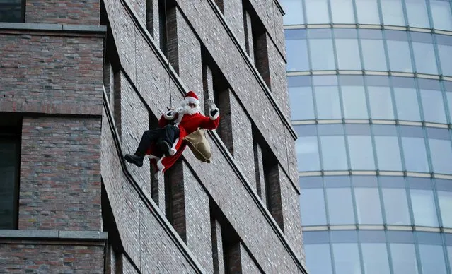 A man dressed as a Santa Claus climbs down from the Kollhoff Tower at Potsdamer Platz square in Berlin, Germany, December 13, 2015. (Photo by Fabrizio Bensch/Reuters)