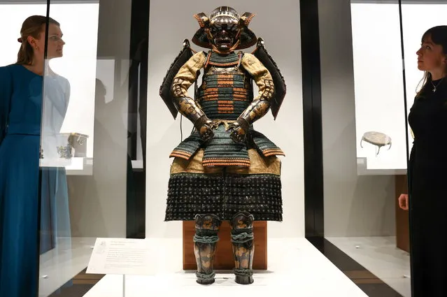 Gallery employees pose with a set of Japanese samurai armor, the first ever diplomatic gift from Japan to Britain and given to Britains King James I in 1613, now on display at the “Japan: Courts & Culture” exhibition at the The Queen's Gallery in London, Britain, April 7, 2022. (Photo by Henry Nicholls/Reuters)