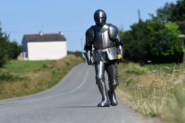 French artist and performer Abraham Poincheval wears a plate armour as he walks on July 9, 2018 in Carnoet, western France. For a few years Poincheval has broadened experiences of confinement such as staying in a statue of man-lion for a week in the museum park of Aurignac, or spending 8 days in a hole under a one-tonne stone and 2 weeks inside a stuffed bear. He now plans to walk 170 kilometers across French Brittany wearing a plate armour like an “erring knight” of the XXI century. (Photo by Fred Tanneau/AFP Photo)
