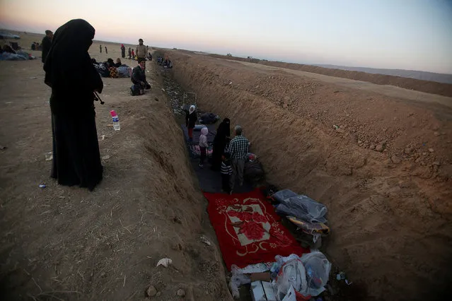 Displaced people from the outskirts of Mosul sleep in a trench in the town of Bashiqa, after it was recaptured from the Islamic State, east of Mosul, Iraq, November 18, 2016. (Photo by Khalid al Mousily/Reuters)