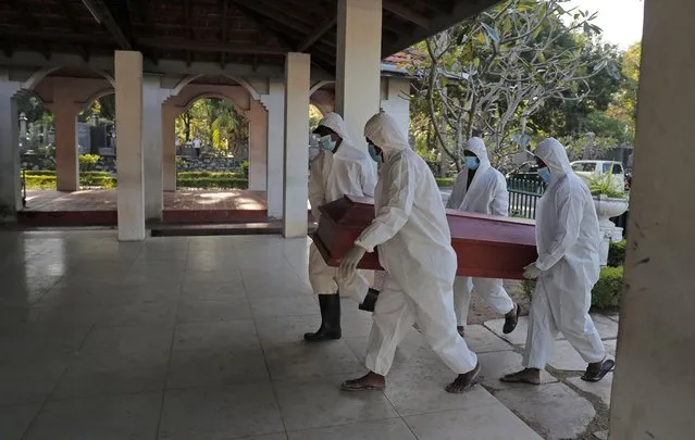 Sri Lankan municipal workers carry the coffin of a COVID-19 victim at a cemetery in Colombo, Sri Lanka, Friday, January 22, 2021. Sri Lanka on Friday approved the Oxford-AstraZeneca vaccine for COVID-19 amid warnings from doctors that front-line health workers should be quickly inoculated to stop the system from collapsing. (Photo by Eranga Jayawardena/AP Photo)