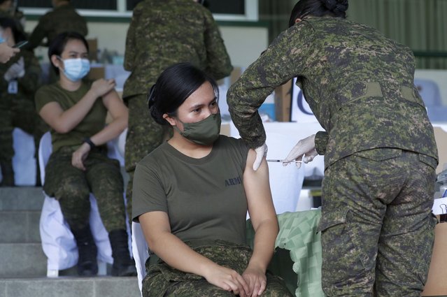 Philippine Army women soldiers are injected with the Sinovac vaccine from China during a vaccination at Fort Bonifacio, Metro Manila, Philippines on Tuesday, March 2, 2021. The Philippines launched a vaccination campaign to contain one of Southeast Asia's worst coronavirus outbreaks but faces supply problems and public resistance, which it hopes to ease by inoculating top officials. (Photo by Aaron Favila/AP Photo)