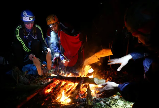 Belarussian tourists warm up by a camp fire as they take part in “Search and rescue operations – 2016”, a three-day competition, near the village of Priselki, Belarus, November 25, 2016. Photo taken November 25, 2016. (Photo by Vasily Fedosenko/Reuters)